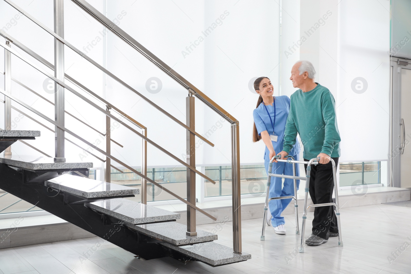 Photo of Nurse assisting senior man with walker in hospital