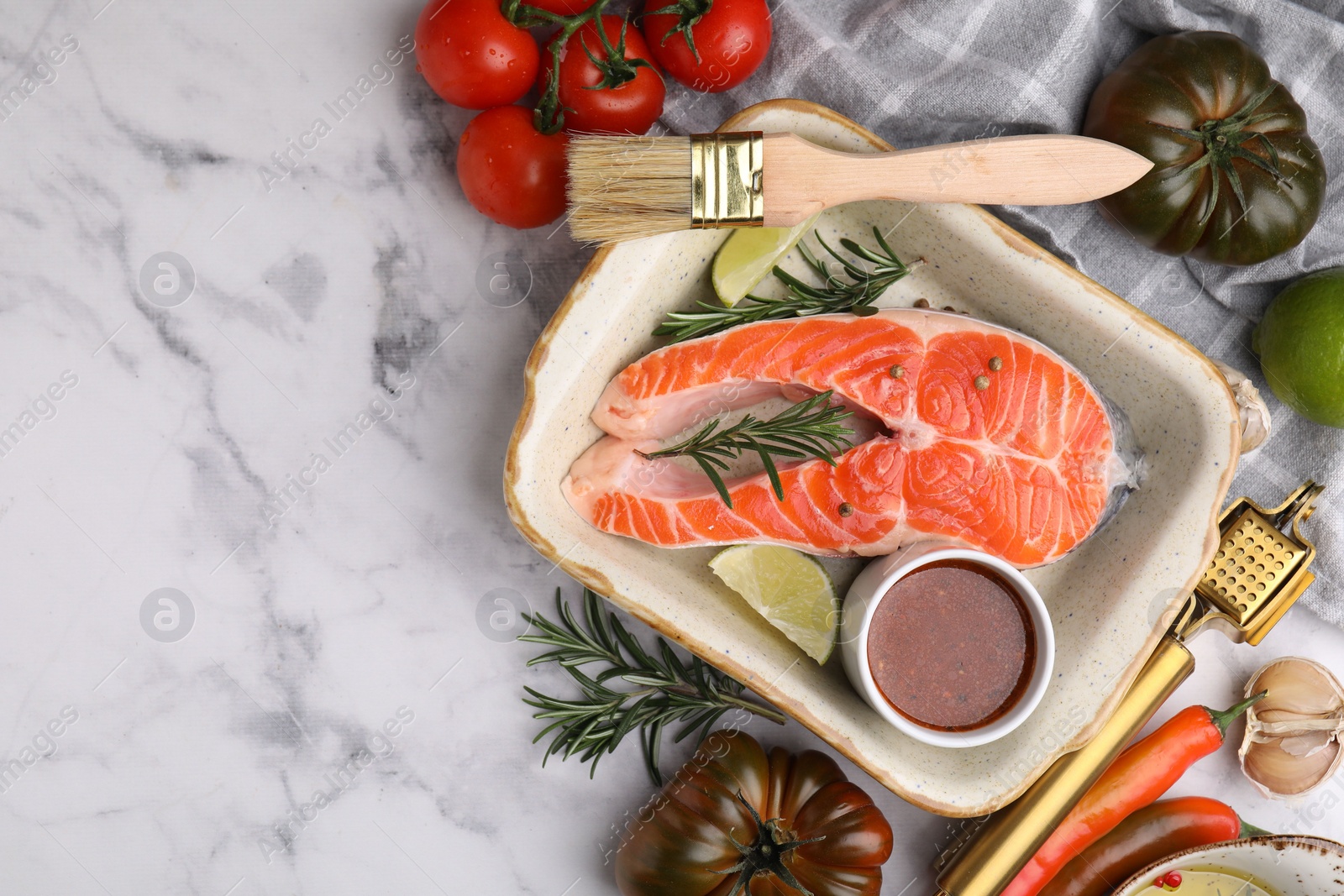 Photo of Fresh fish, lime, rosemary, marinade in baking dish and other products on light marble table, flat lay. Space for text