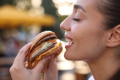 Lviv, Ukraine - September 26, 2023: Woman eating McDonald's burger outdoors, closeup