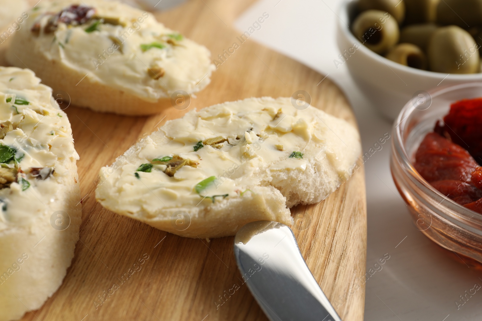 Photo of Tasty butter with olives, green onion and knife on table, closeup