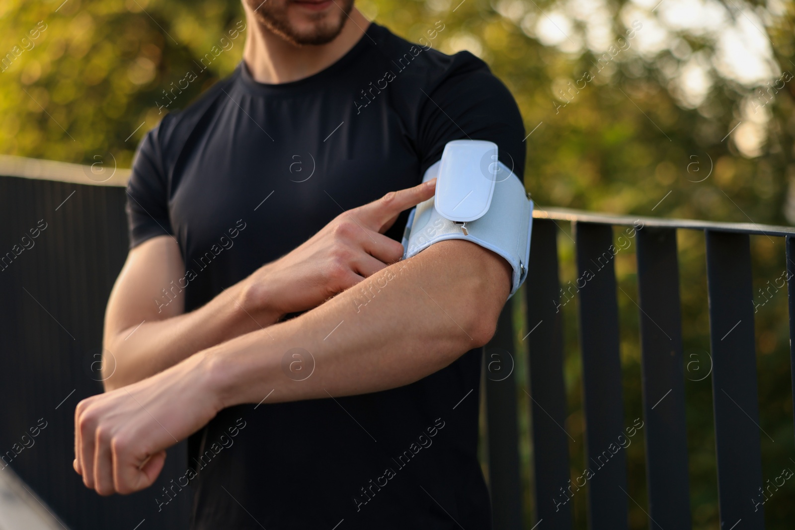 Photo of Man checking blood pressure with modern monitor outdoors, closeup