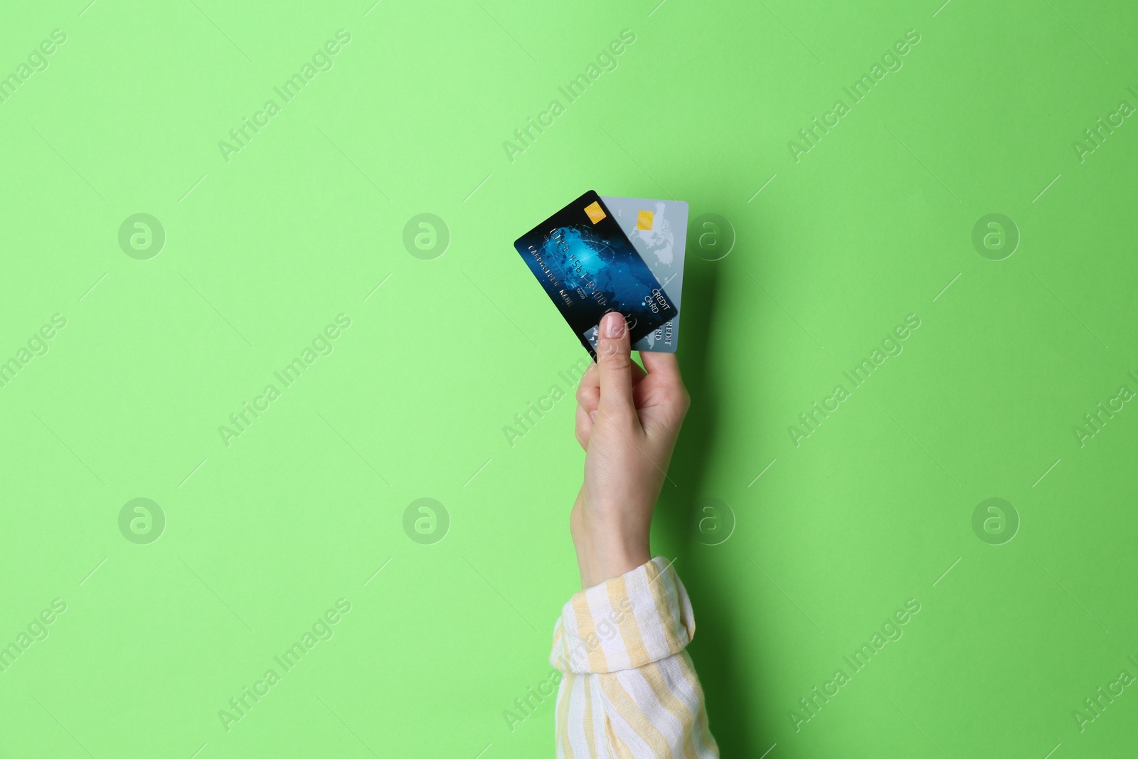 Photo of Woman holding credit cards on light green background, closeup