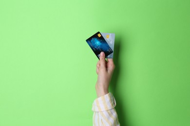 Photo of Woman holding credit cards on light green background, closeup