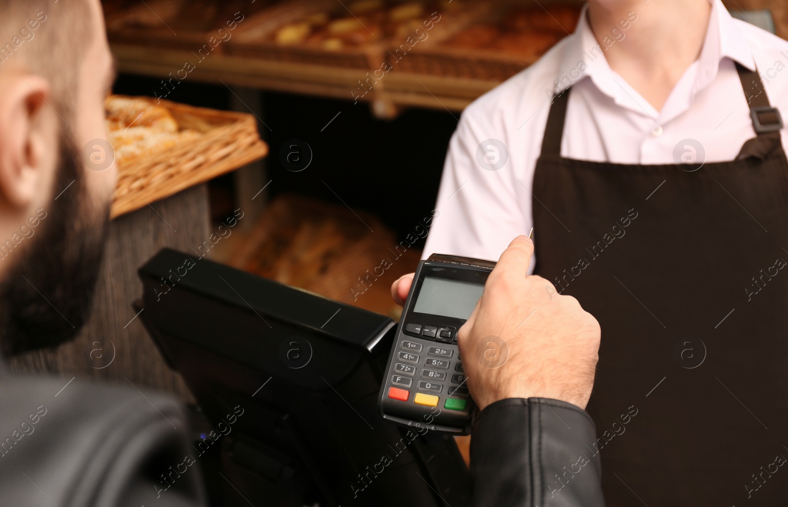 Photo of Man with credit card using payment terminal at shop, closeup