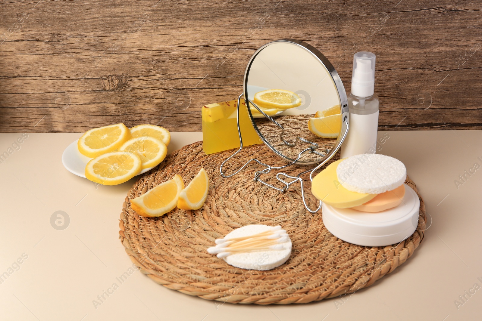 Photo of Lemon face cleanser. Fresh citrus fruits, personal care products and mirror on beige table