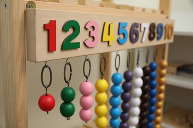 Montessori toy with color bead lines and numbers on wooden stand in room, closeup