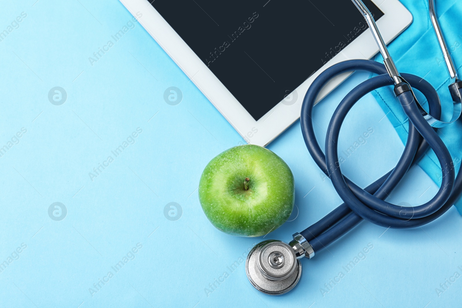 Photo of Stethoscope, tablet and apple on color background. Medical equipment