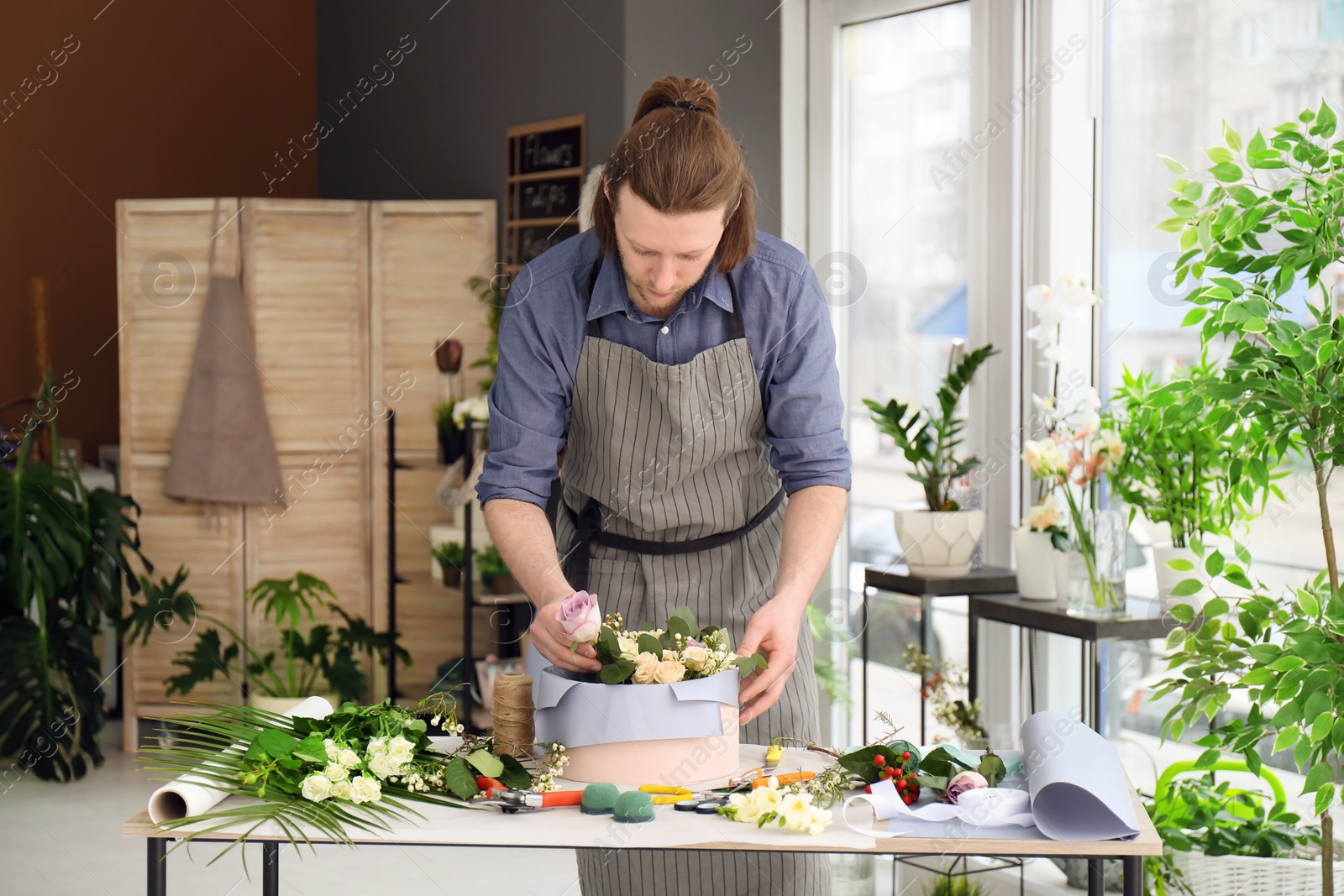 Photo of Male florist creating floral composition at workplace