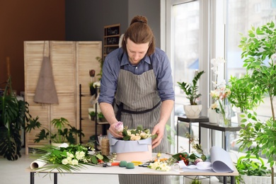 Photo of Male florist creating floral composition at workplace