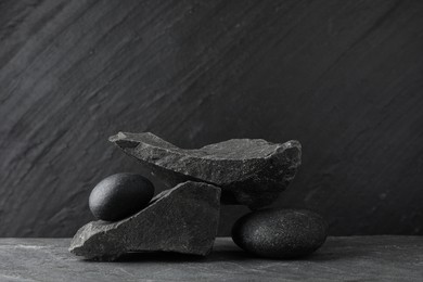 Photo of Presentation for product. Podium made of different stones on grey textured background. Space for text