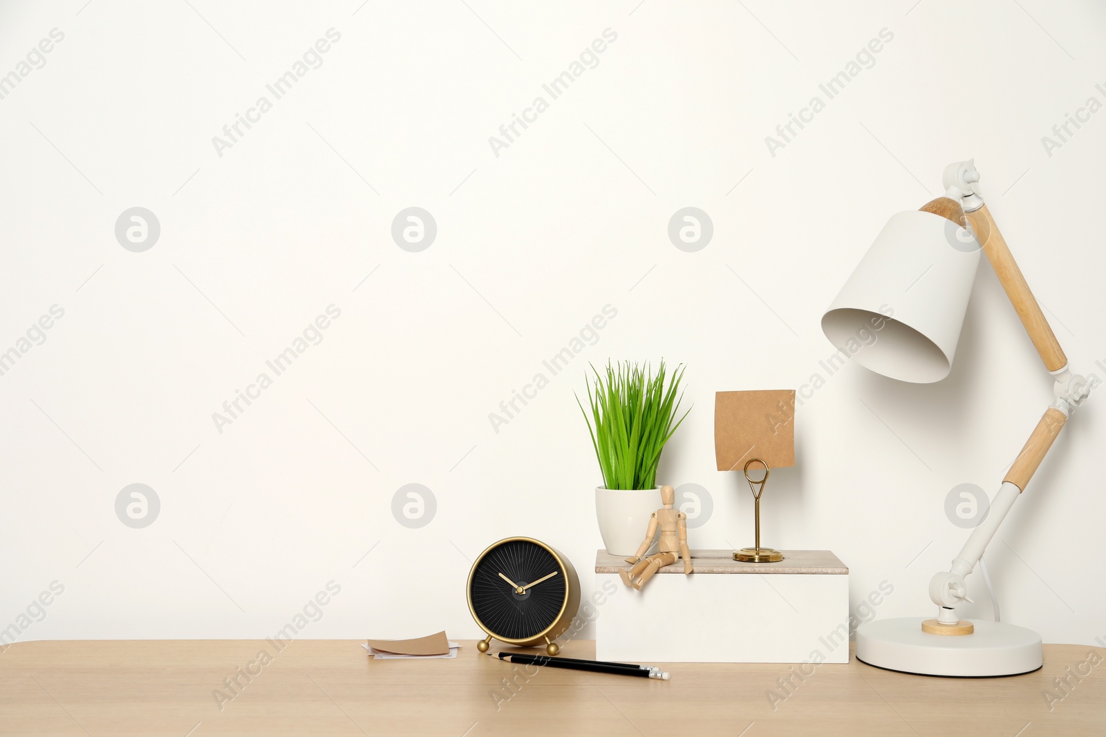 Photo of Comfortable workplace with wooden desk near white wall. Space for text