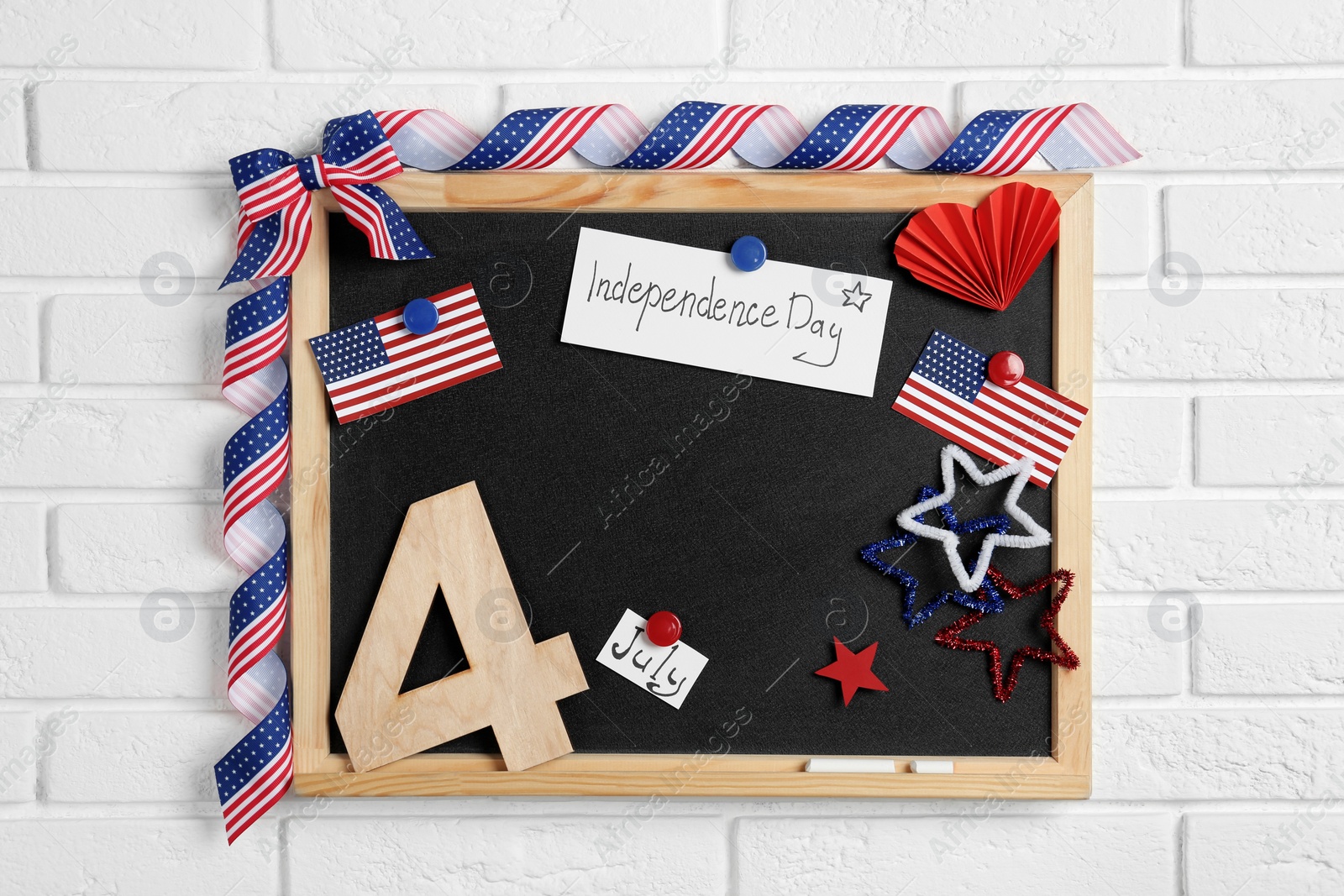 Photo of Blackboard with cards, wooden number and USA flags hanging on brick wall. Happy Independence Day