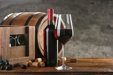 Winemaking. Composition with tasty wine and barrel on wooden table against gray background, space for text