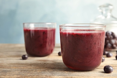 Photo of Glasses with delicious acai smoothie on wooden table, closeup