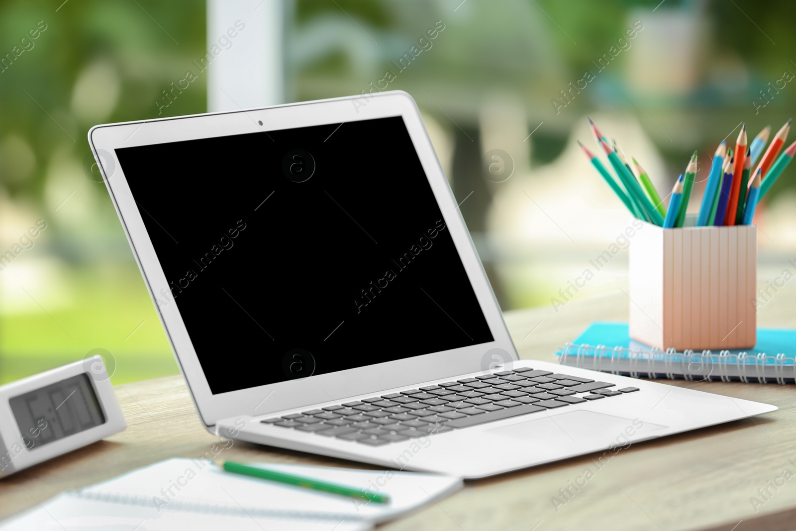 Photo of Modern laptop on table against window. Mock up with space for text