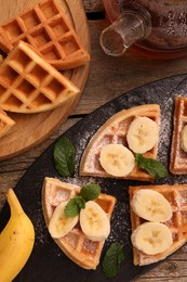 Tasty Belgian waffles with banana and mint on wooden table, flat lay