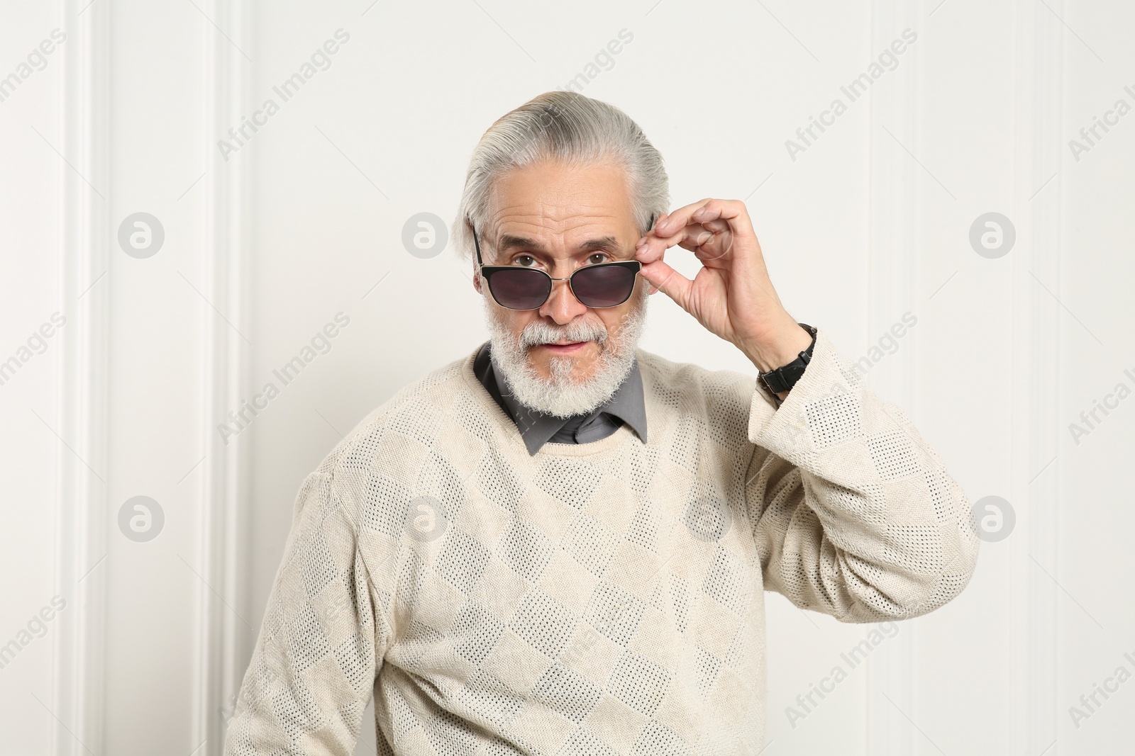 Photo of Portrait of handsome senior man in stylish sunglasses near white wall