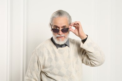 Photo of Portrait of handsome senior man in stylish sunglasses near white wall