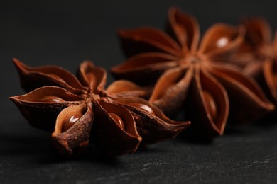 Photo of Aromatic anise stars on black table, closeup