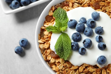 Delicious yogurt with granola and blueberries in bowl on grey table, top view