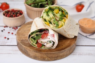 Photo of Delicious sandwich wraps with fresh vegetables and sauce on white wooden table, closeup