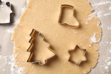 Photo of Making Christmas cookies. Raw dough and metal cutters on parchment paper, flat lay