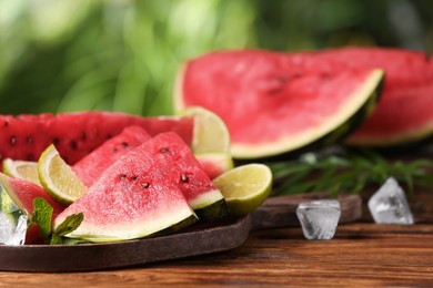 Photo of Slices of delicious ripe watermelon, ice cubes and cut lime on wooden table outdoors, closeup. Space for text