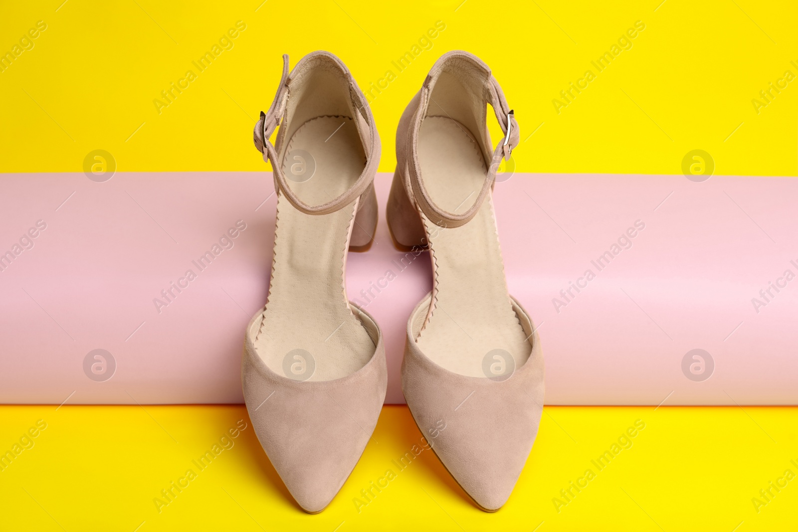 Photo of Stylish pink female shoes on yellow background