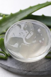 Photo of Aloe vera gel and slices of plant on white background, closeup