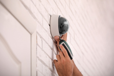 Photo of Technician installing CCTV camera on wall, closeup