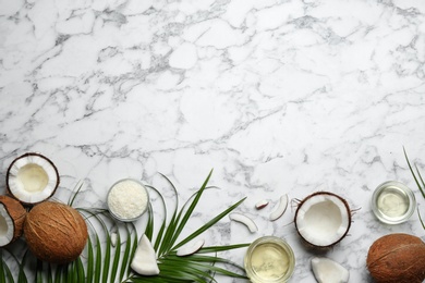 Jars of natural organic oil and coconuts on marble background, flat lay. Space for text