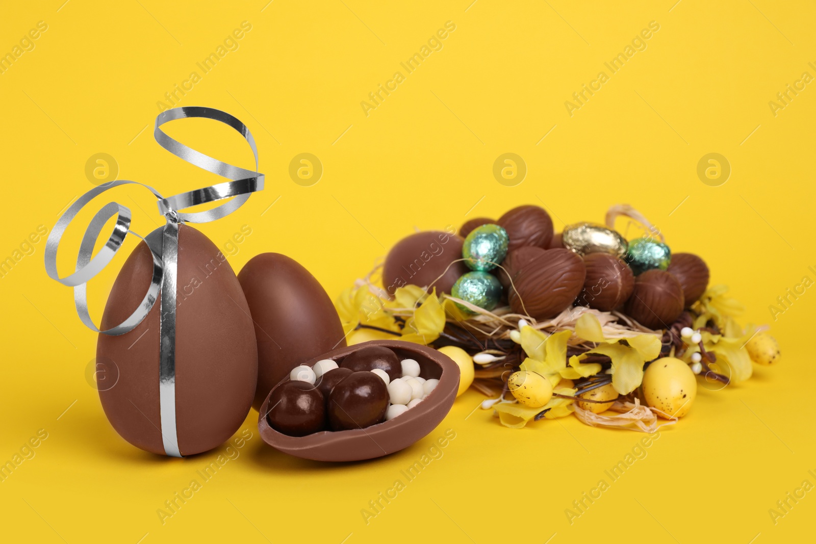 Photo of Delicious chocolate eggs and sweets on yellow background