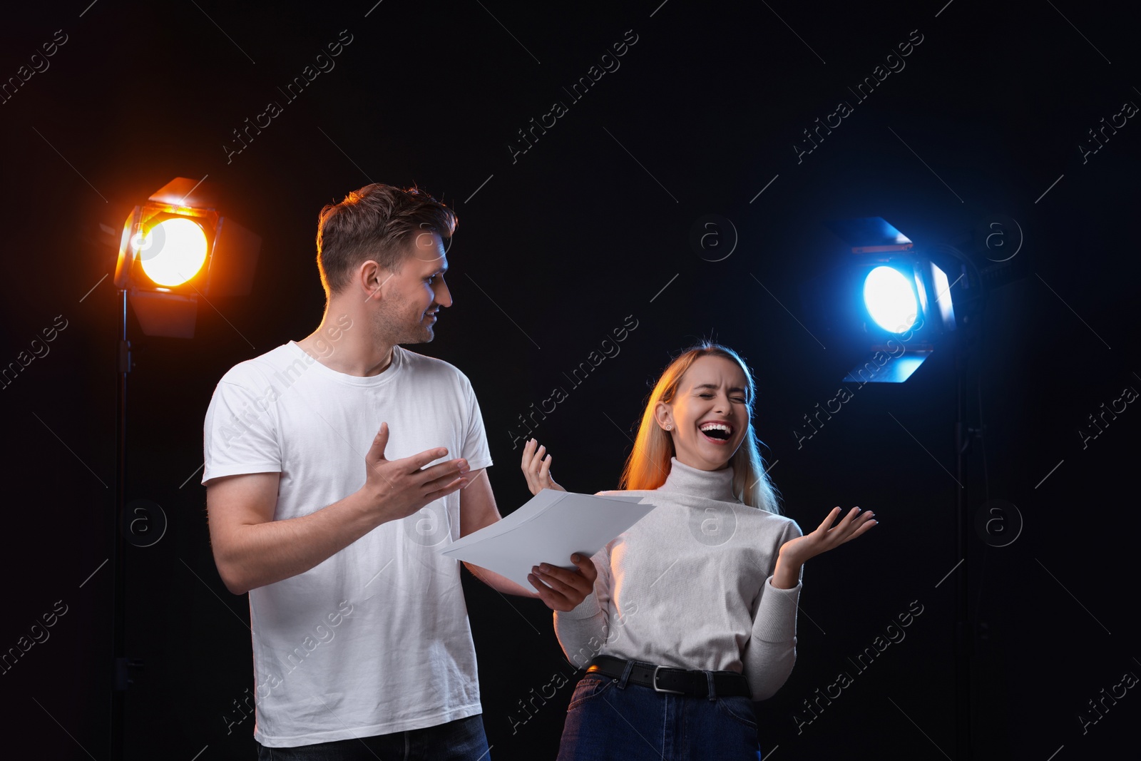 Photo of Casting call. Emotional woman and man with script performing on black background