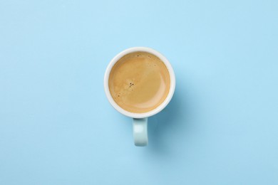 Photo of Aromatic coffee in cup on light blue background, top view