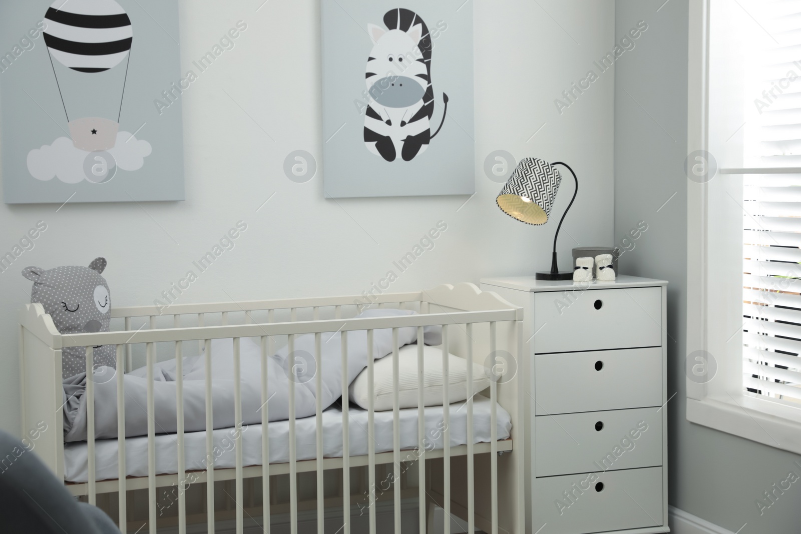 Photo of Stylish baby room interior with crib and chest of drawers