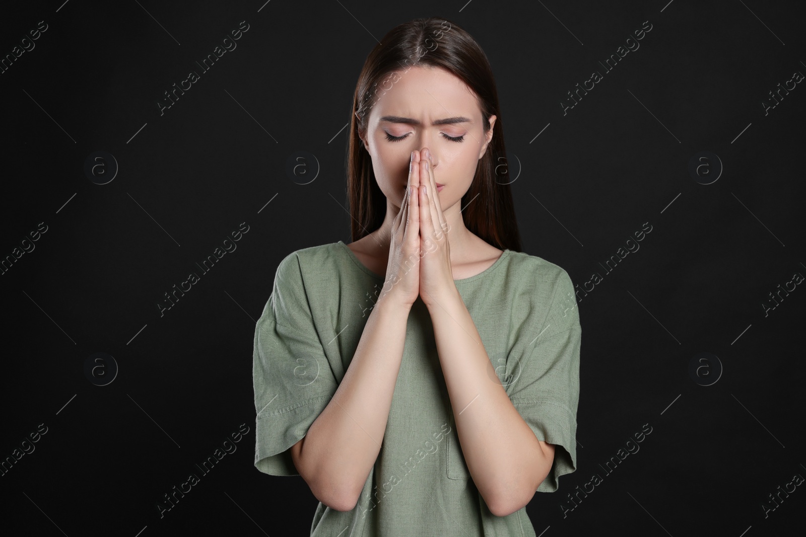 Photo of Woman with clasped hands praying on black background