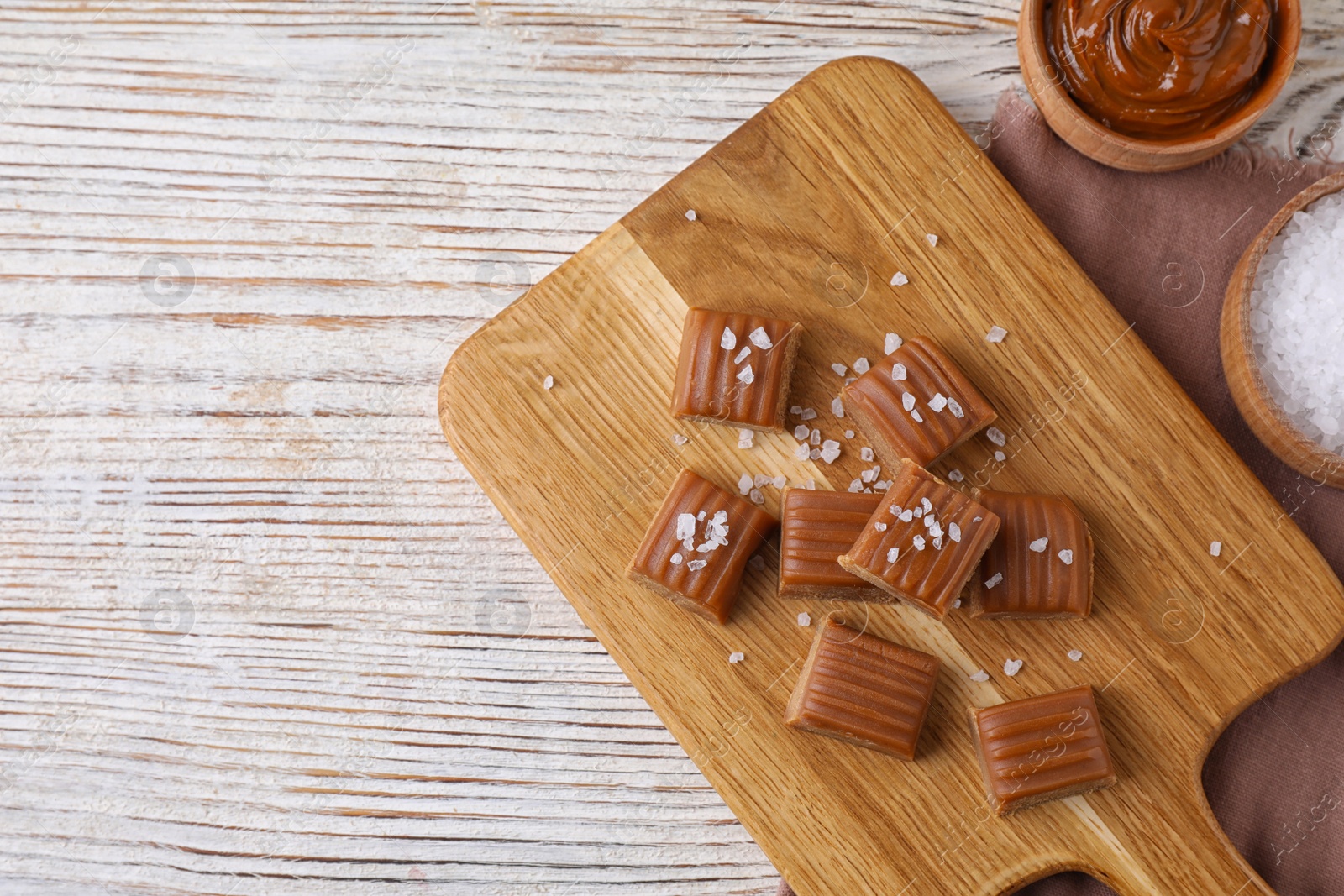Photo of Delicious salted caramel on white wooden table, flat lay