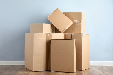 Photo of Pile of cardboard boxes near light blue wall indoors