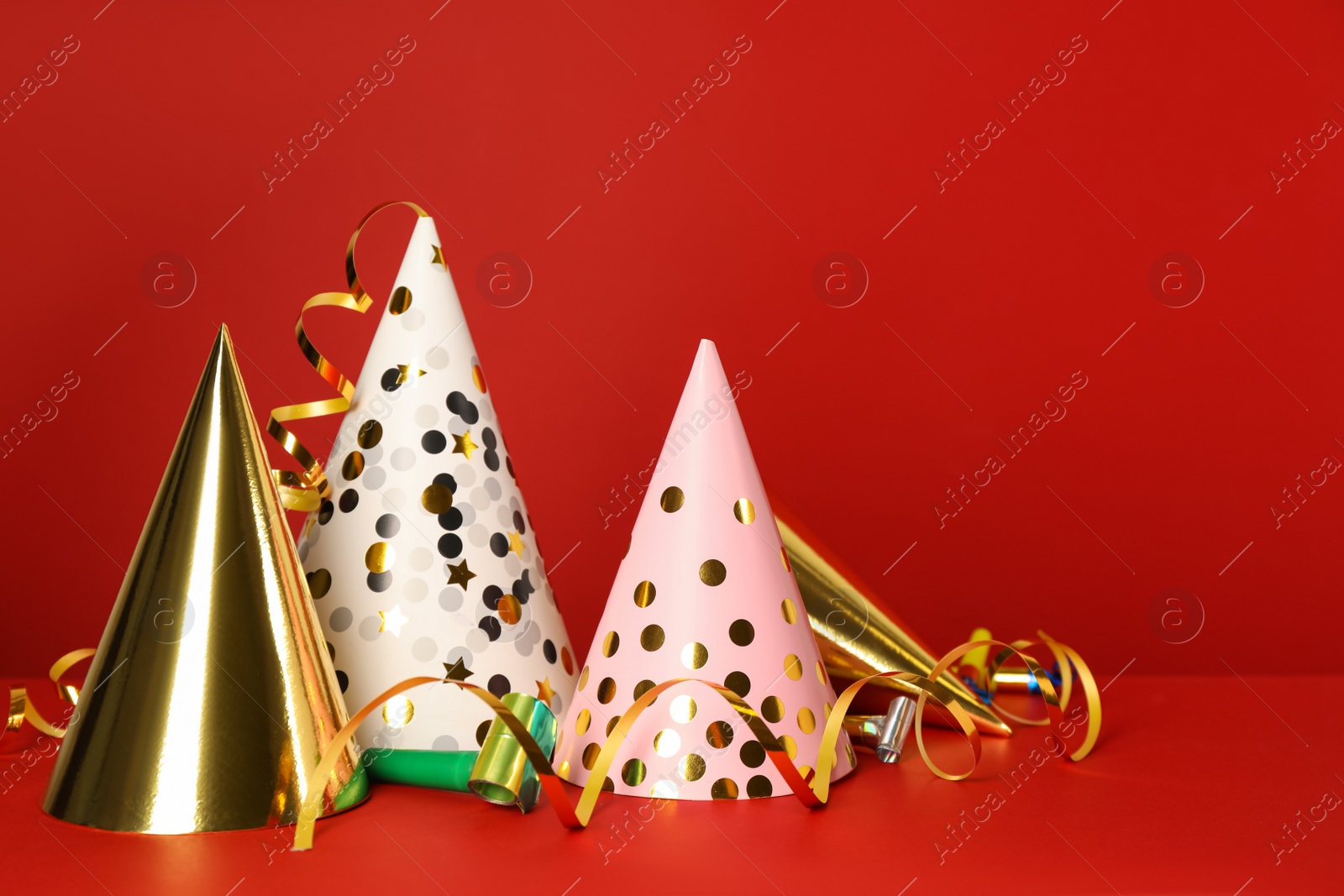 Photo of Party hats and festive items on red background. Space for text