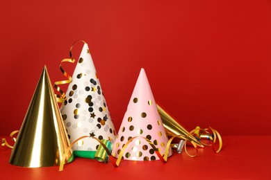 Photo of Party hats and festive items on red background. Space for text