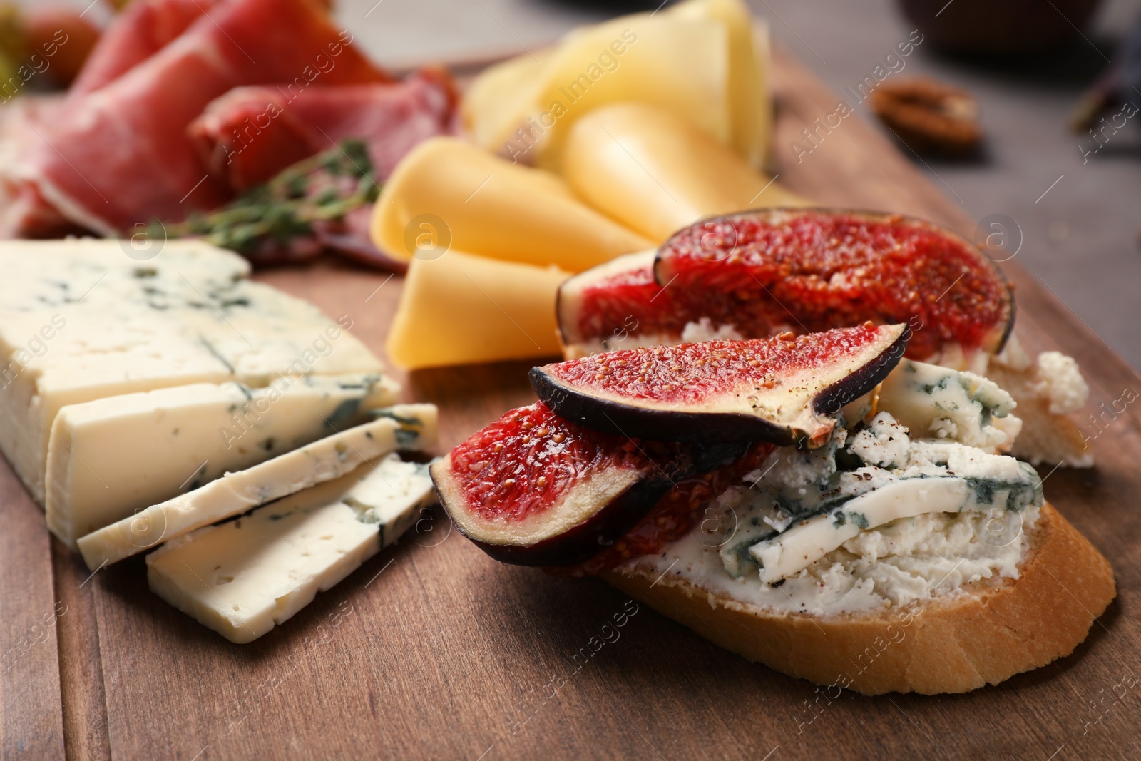 Photo of Sandwich with ripe fig and cheese on wooden board, closeup