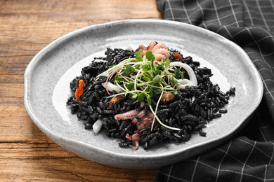 Photo of Delicious black risotto with seafood on wooden table