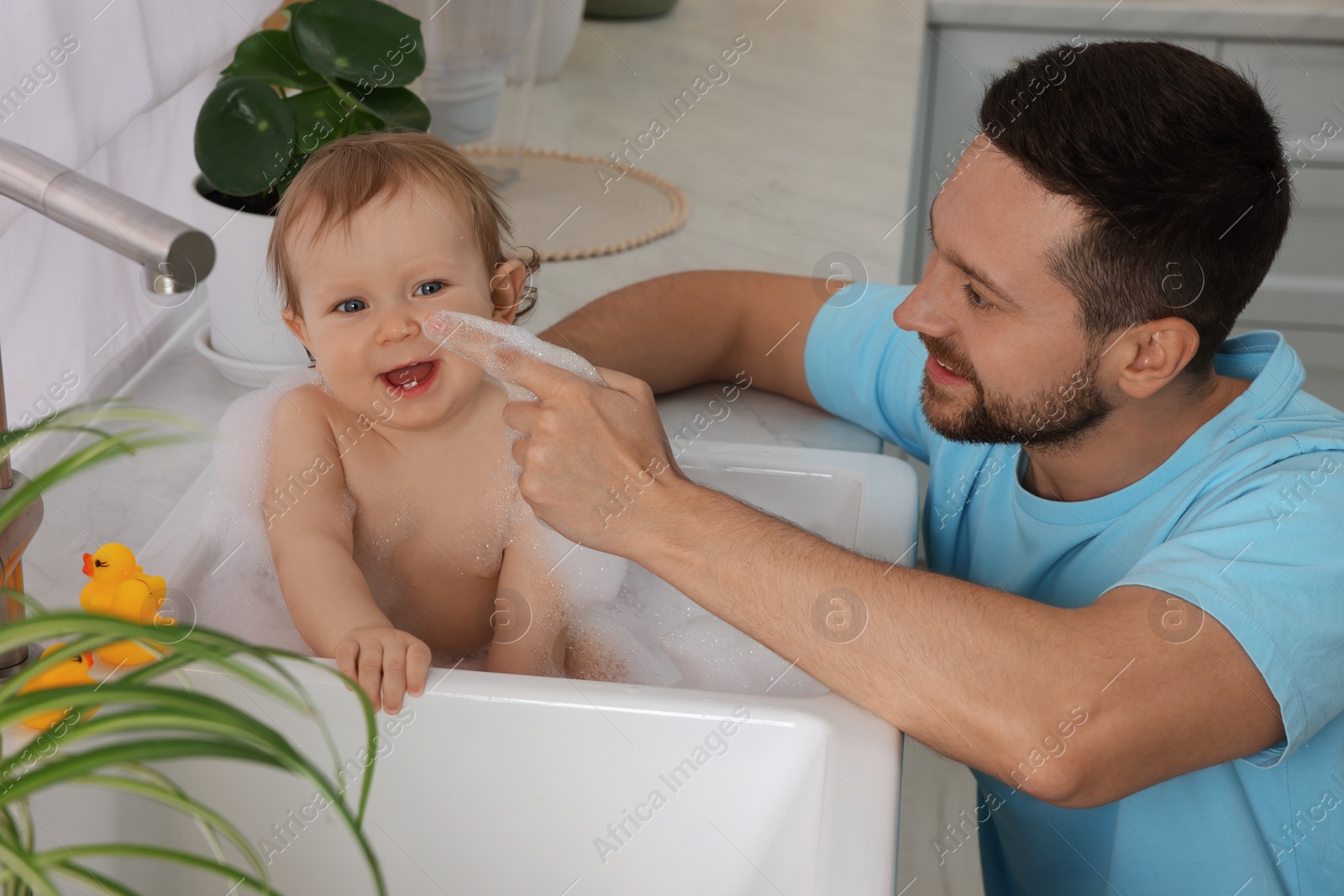 Photo of Father washing his little baby in sink at home