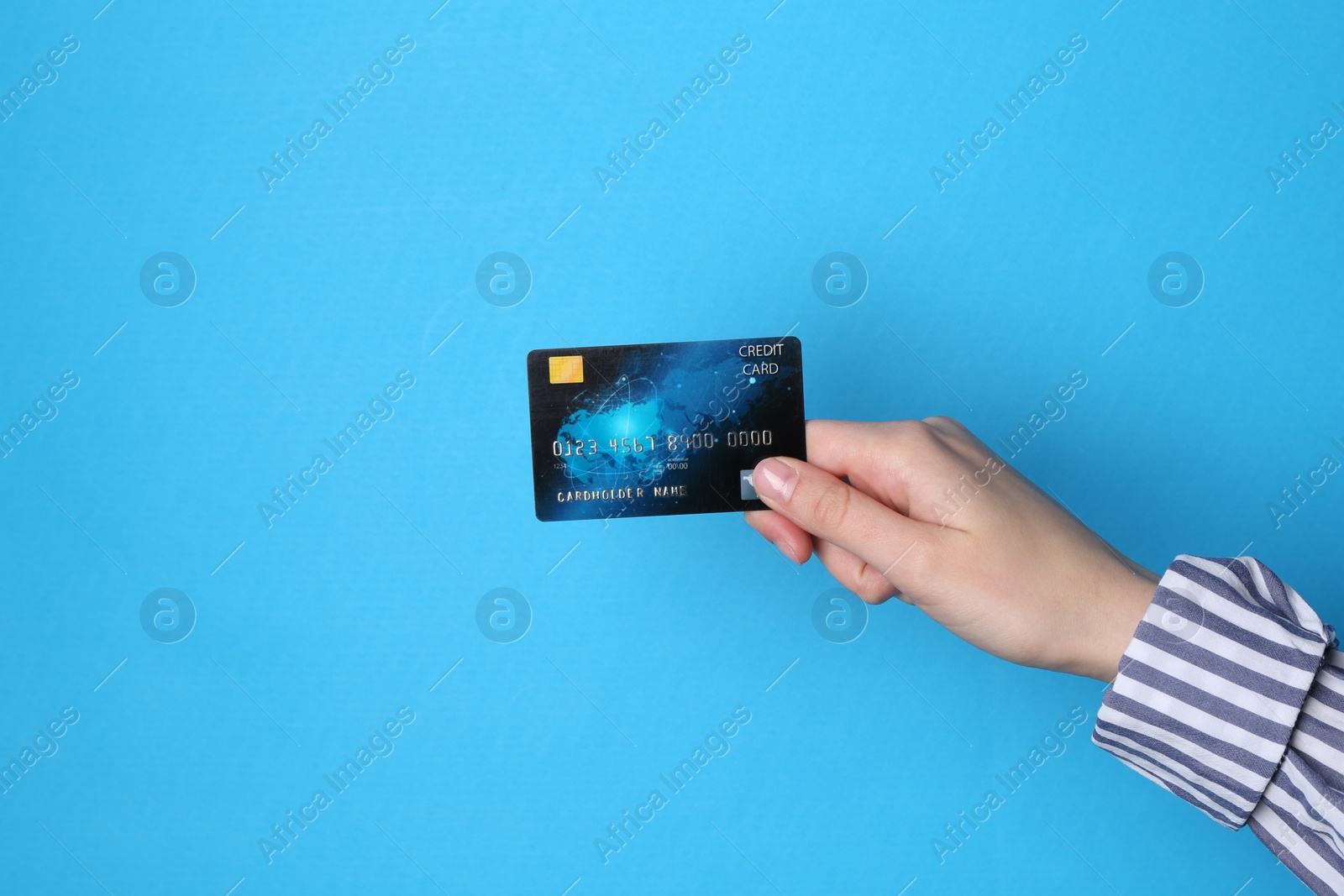 Photo of Woman holding credit card on light blue background, closeup