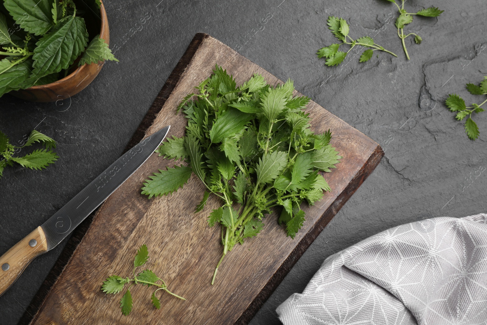 Photo of Fresh stinging nettle leaves on black table, flat lay