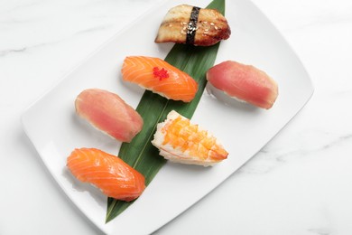 Photo of Plate with delicious nigiri sushi on white marble table, top view