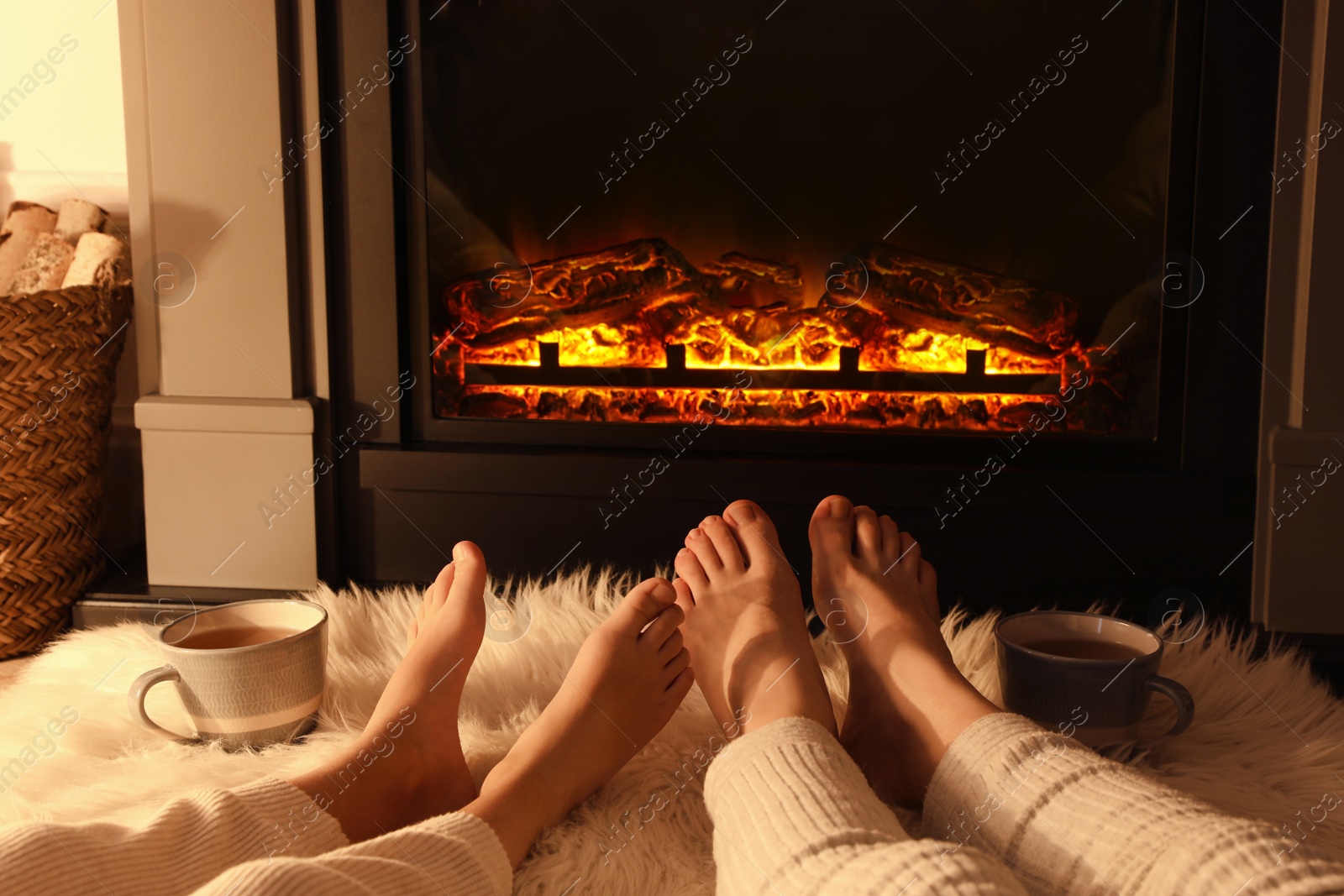 Photo of Couple resting near fireplace at home, closeup of legs