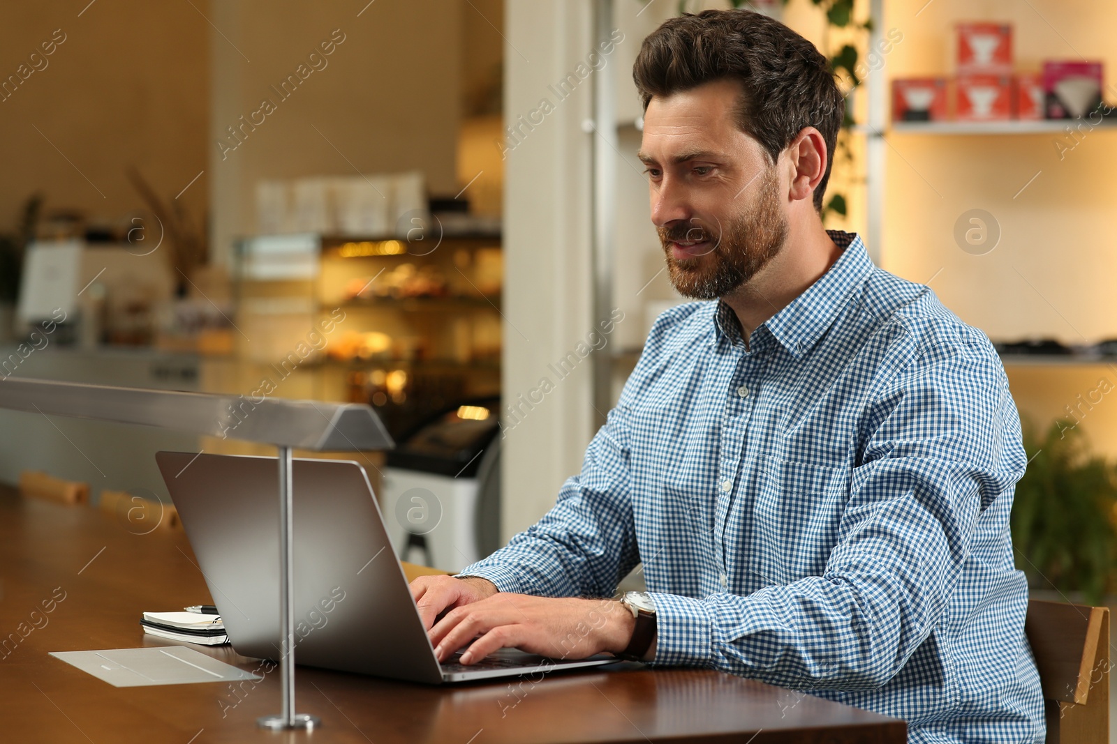 Photo of Man working on laptop at table in cafe