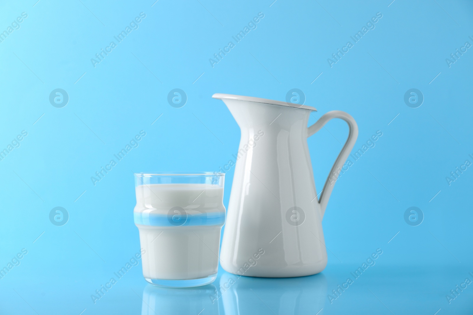 Photo of Glass of fresh milk and jug on light blue background