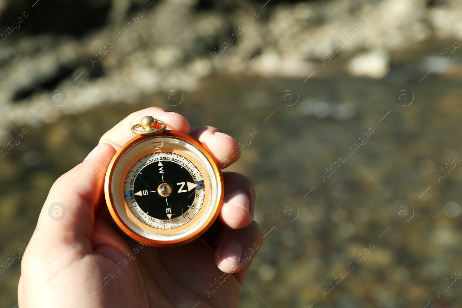 Photo of Man using compass for navigation during journey outdoors, closeup